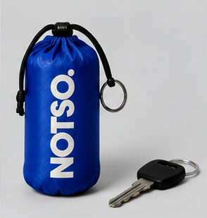 Miniature blue NOTSO. pouch beside keys